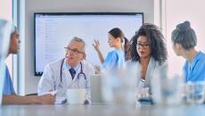 Healthcare workers meeting with large screen in background