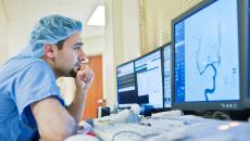 Healthcare worker in scrubs looking at medical image on screen