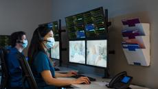 Healthcare workers in masks viewing patients on monitors