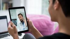 A doctor appears on a tablet having a telehealth visit with a person with short hair.